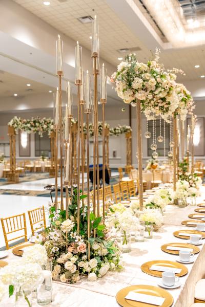 A large wedding setup with towering candelabra centerpieces, white and pink florals, gold accents, and crystals. 