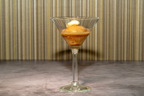 A golden colored sorbet served in a martini glass.