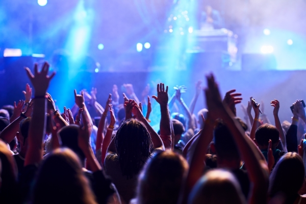 A large crowd of people with raised hands facing a blue lit stage at a concert. Enjoy concerts with Orlando's thriving music scene.