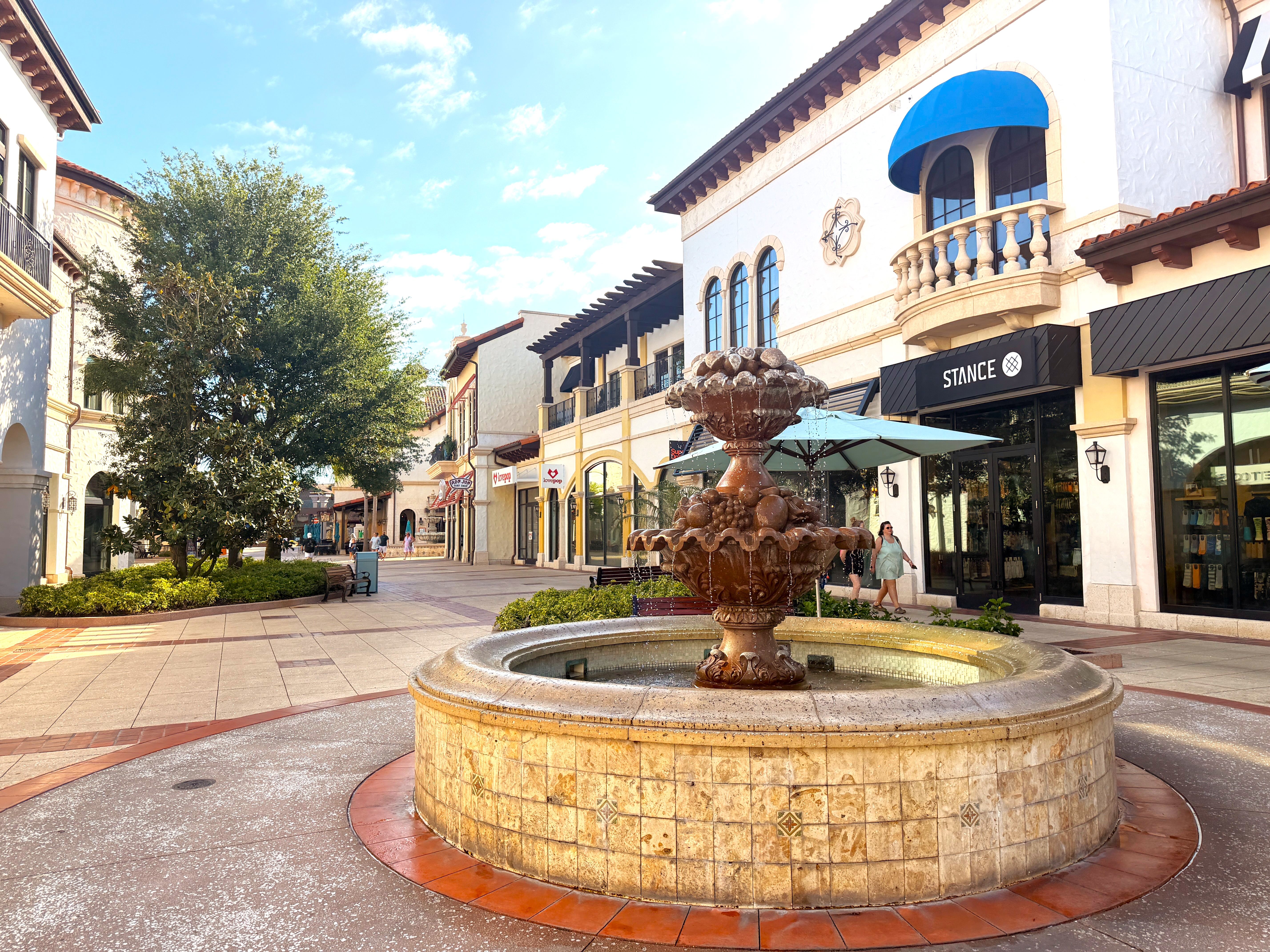 A fountain on a cobblestone street surrounded by Mediterranean-style shops at Disney Springs, one of the Orlando attractions near Rosen Centre.