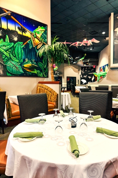 A round table set with white linens and green napkins in Everglades, a restaurant decorated with colorful Floridian artwork. 
