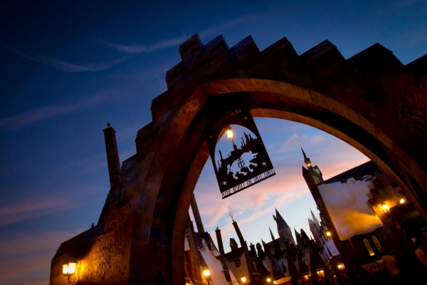 The gates of Hogsmeade and the peaks of village rooftops, glowing at twilight.