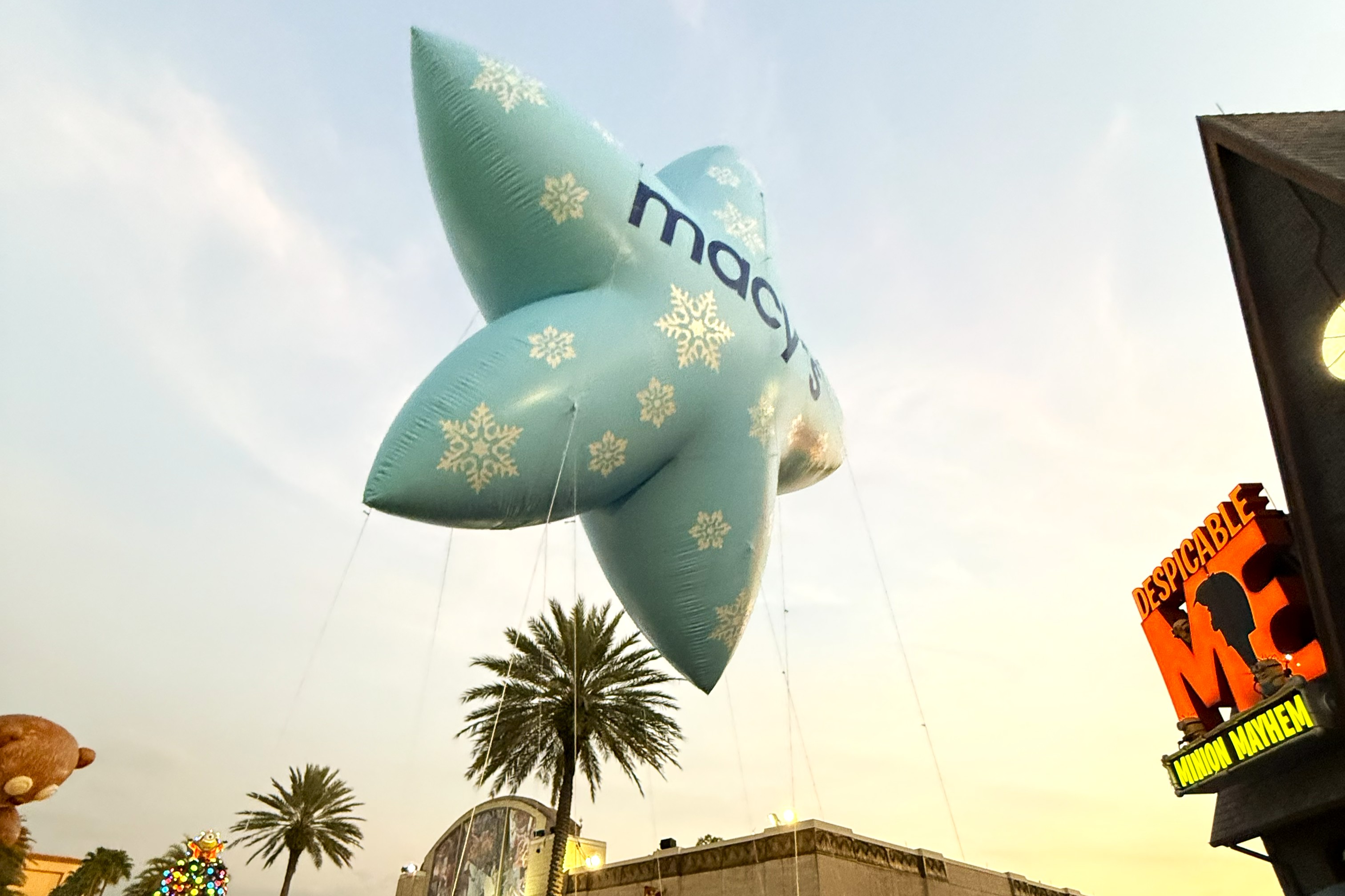A light blue star shaped parade balloon floats against a sunset sky at Universal Orlando during the holidays.