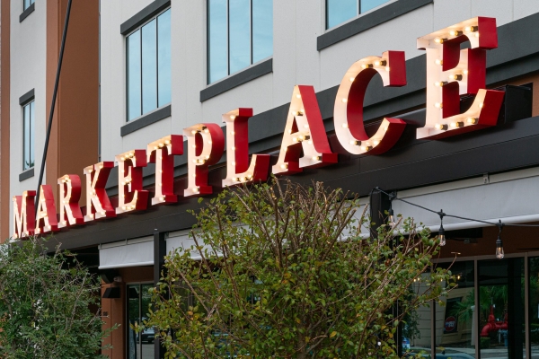 A lit sign on the outside of a building that reads MARKETPLACE in red lit letters.