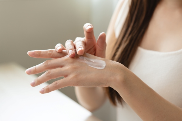 A close-up of a young woman rubbing lotion into her hand.