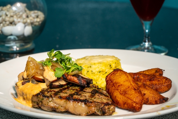 A plate with a grilled steak topped with mushrooms, beside rice and plantains for Magical Dining 2026.