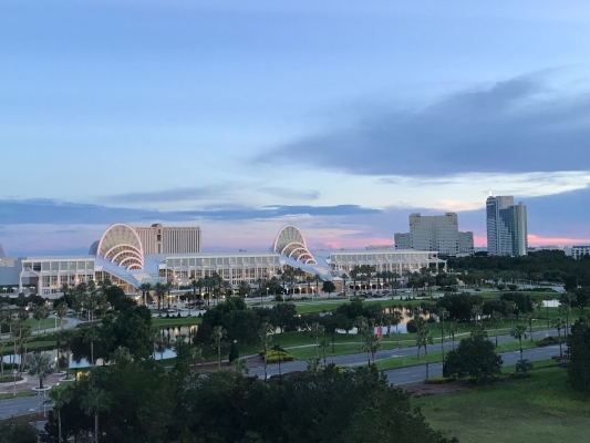 The white glass arches of the Orange County Convention Center with tall buildings in the distance at twilight.