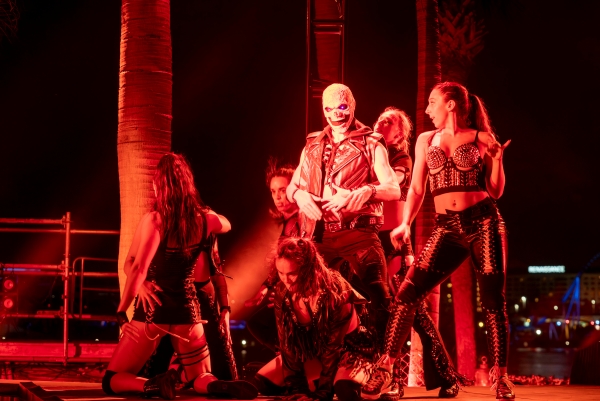 A group of corseted performers gather around a man in a skull mask during a performance at Howl O Scream at SeaWorld Orlando.