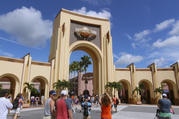 The large towering entryway to Universal Studios Florida on a sunny day with minimal crowds walking beneath.