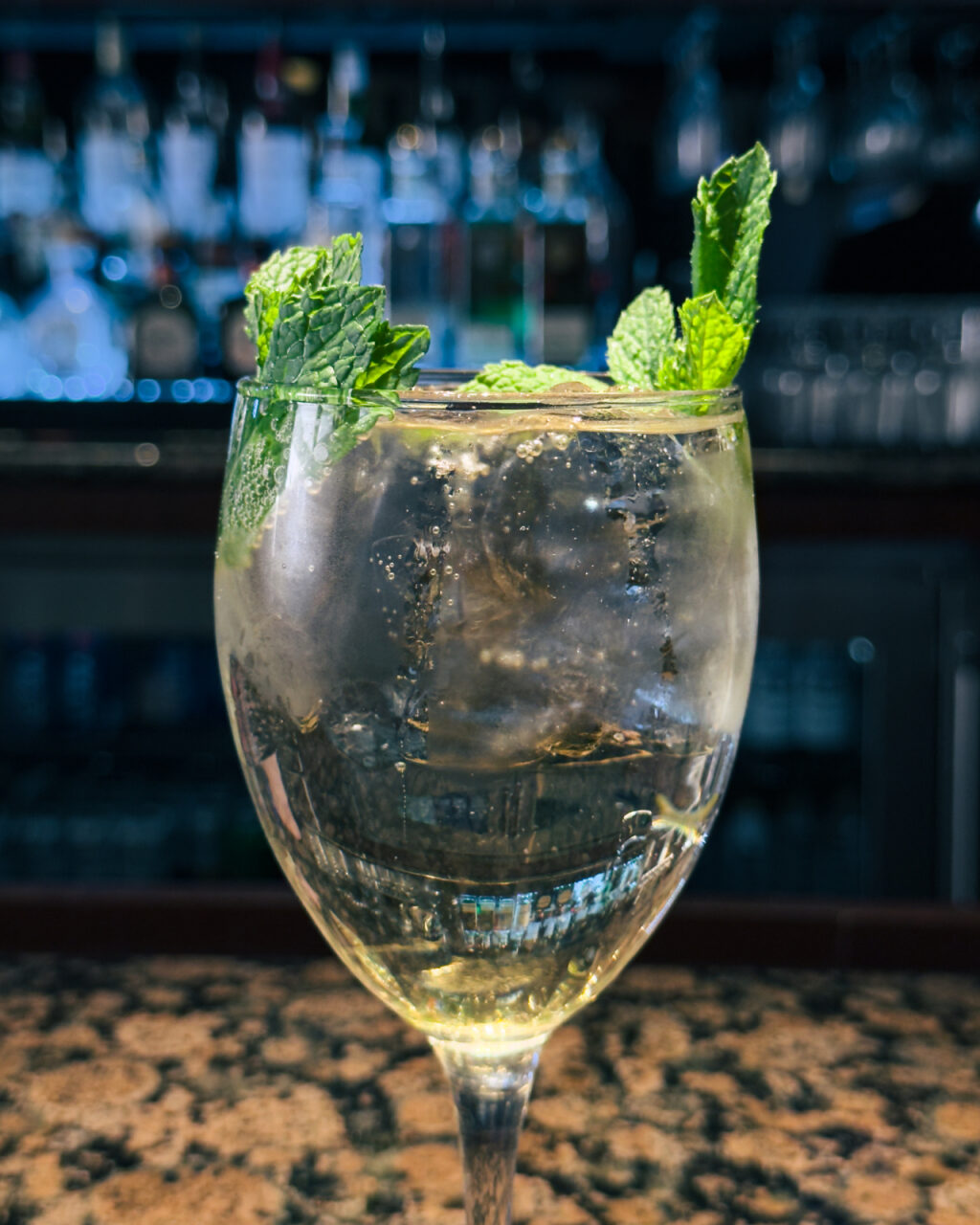 A clear cocktail garnished with mint sprigs. 