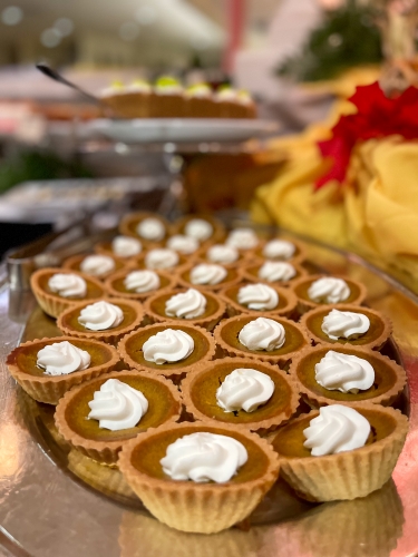 A close-up of a silver platter of mini pumpkin pies with dollops of whipped cream, the finishing touch to the Rosen Centre Thanksgiving buffet.