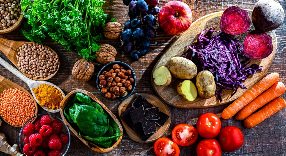 An overhead shot of an assortment of colorful fruits, grains, and vegetables, all examples of food rich in antioxidants. 